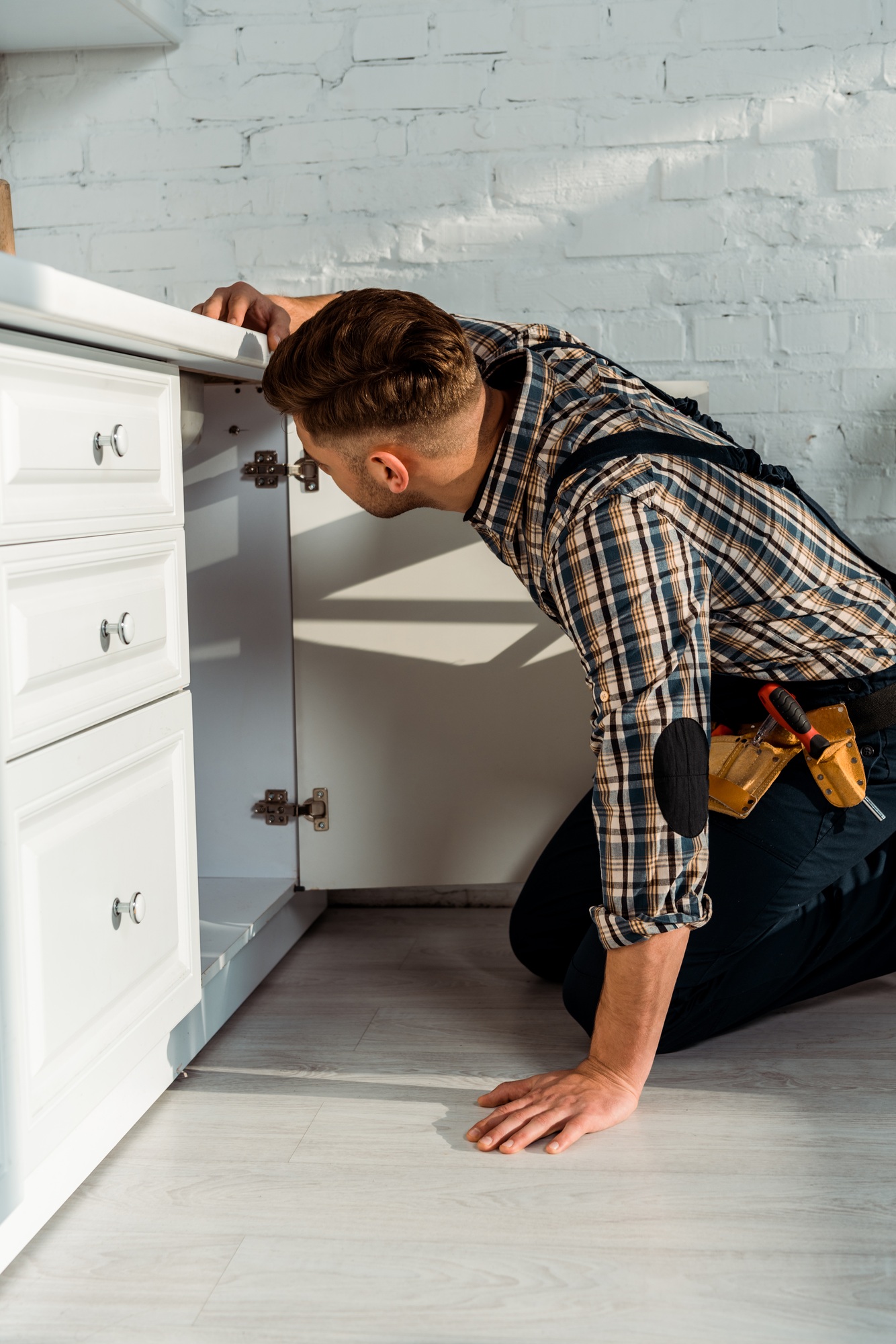 installer sitting near white kitchen cabinet